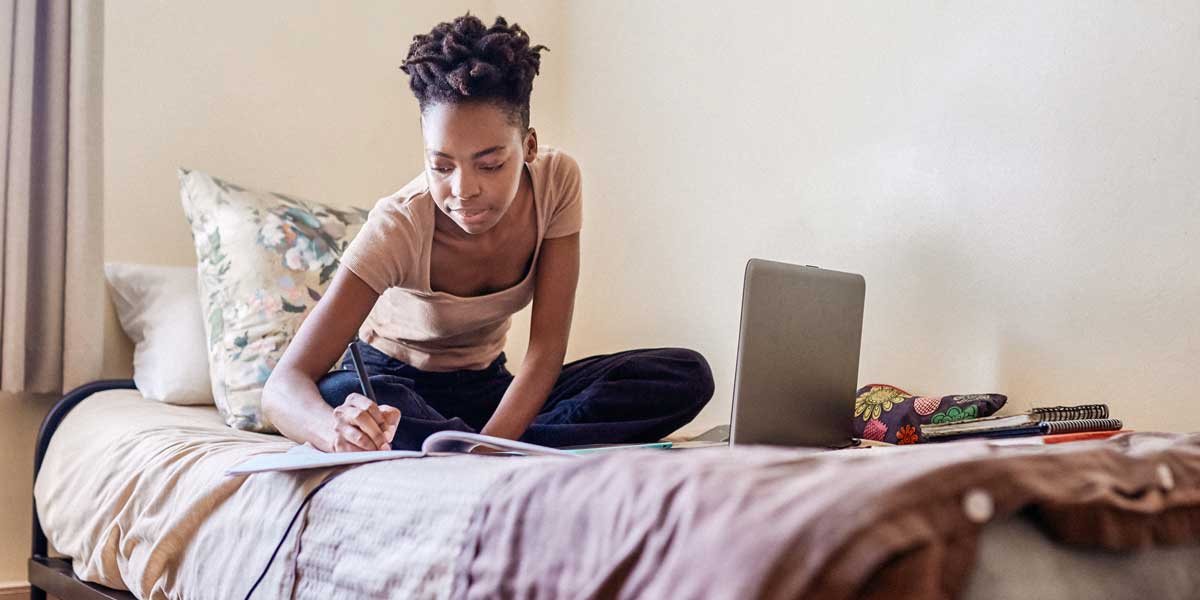 student writing on a bed